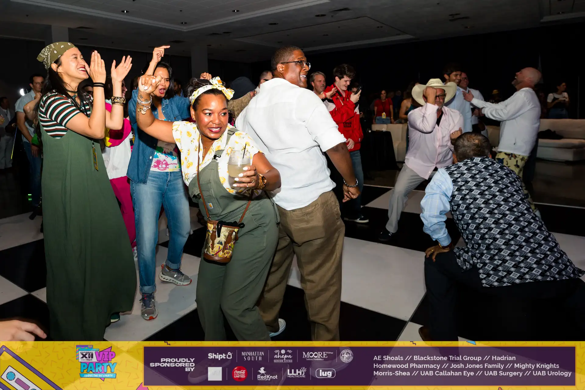 A group of people dancing at a party with a woman holding a drink.