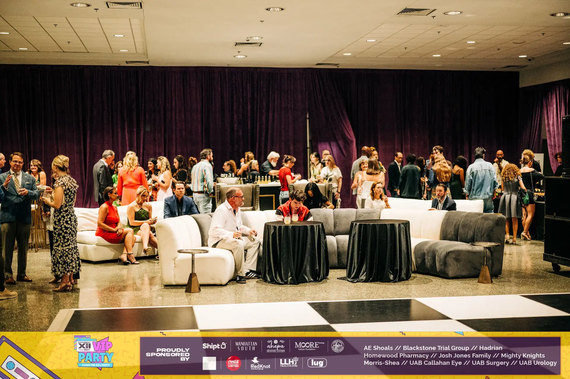 A large group of people are gathered in a room, enjoying drinks and socializing. The event appears to be a high-end gathering, with a focus on specialty drinks and catering services.