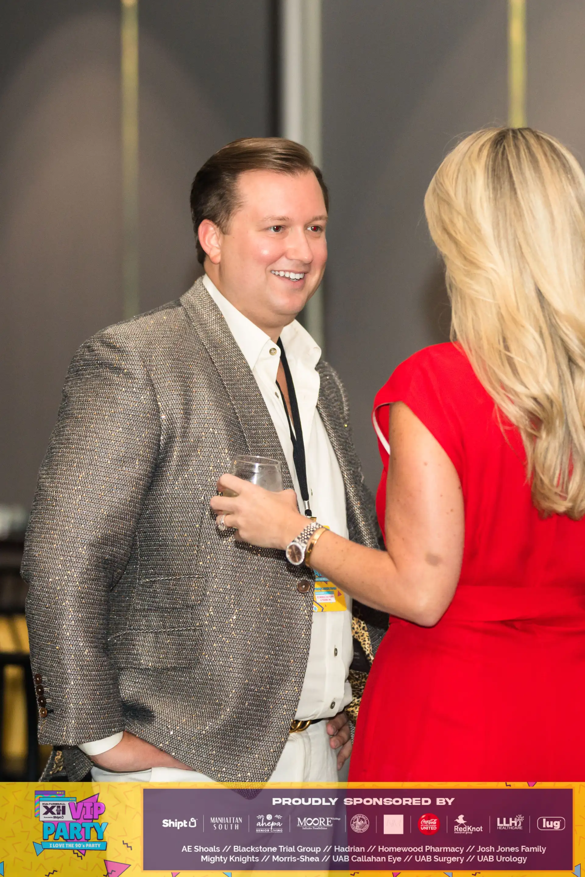 A man in a suit holding a glass of lemonade, smiling at a woman in a red dress.
