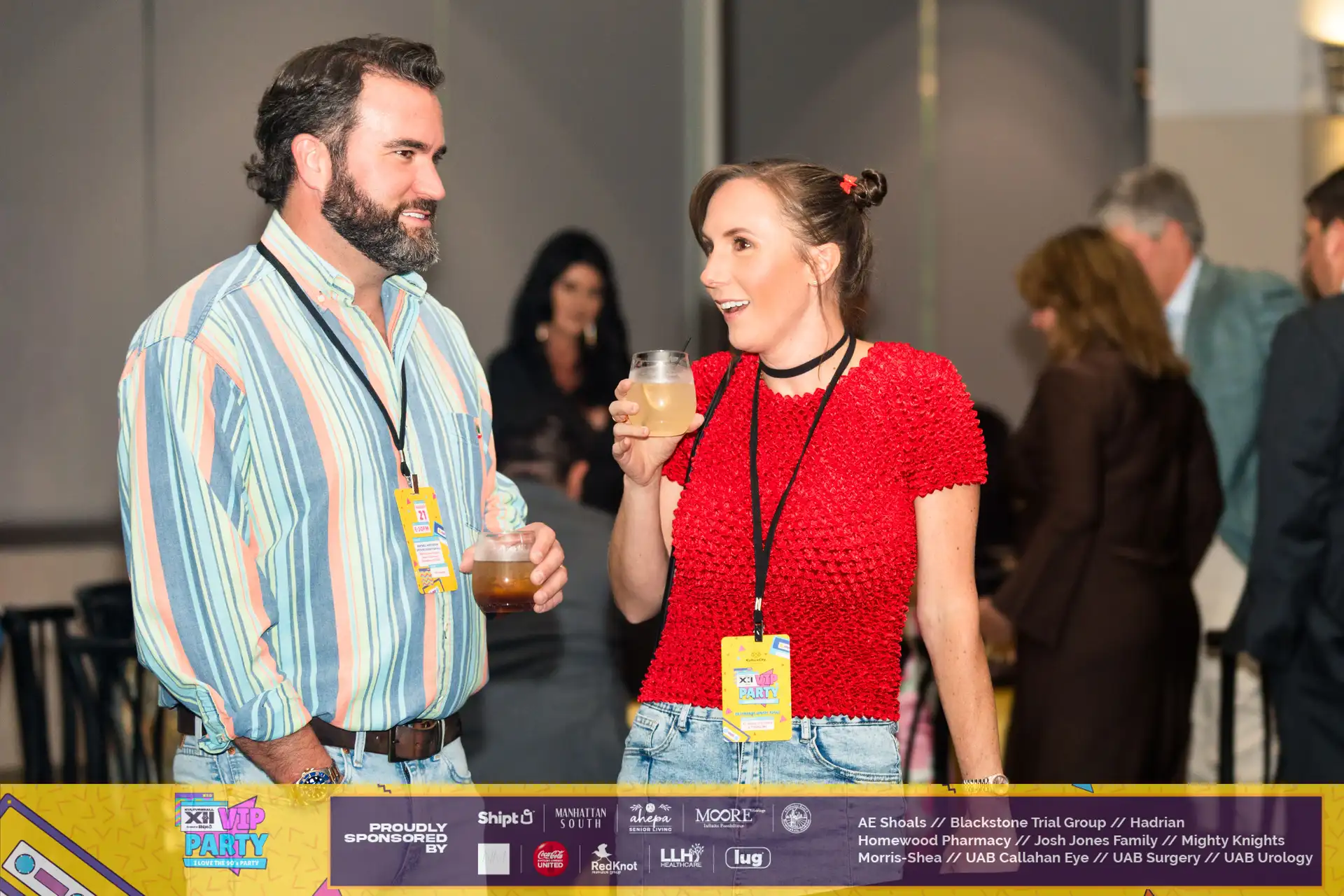 A man and woman are enjoying drinks at a party, with the man holding a glass of lemonade. They are standing in front of a catering table, which is part of the Touch O Magic Lemonade catering service.