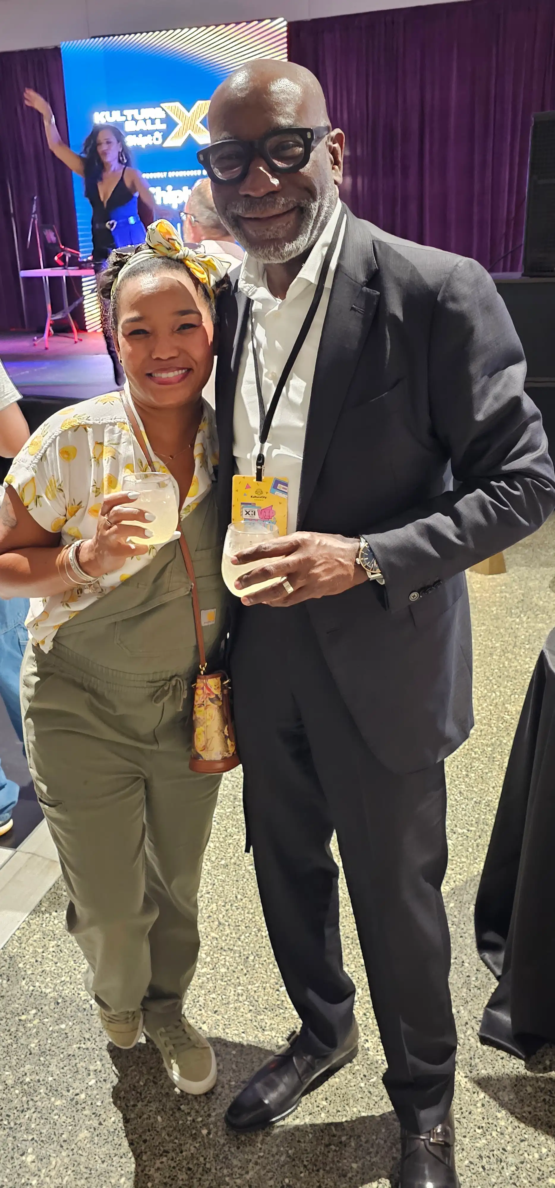 A man and woman standing together, both holding glasses of lemonade, smiling and enjoying their time at an event.
