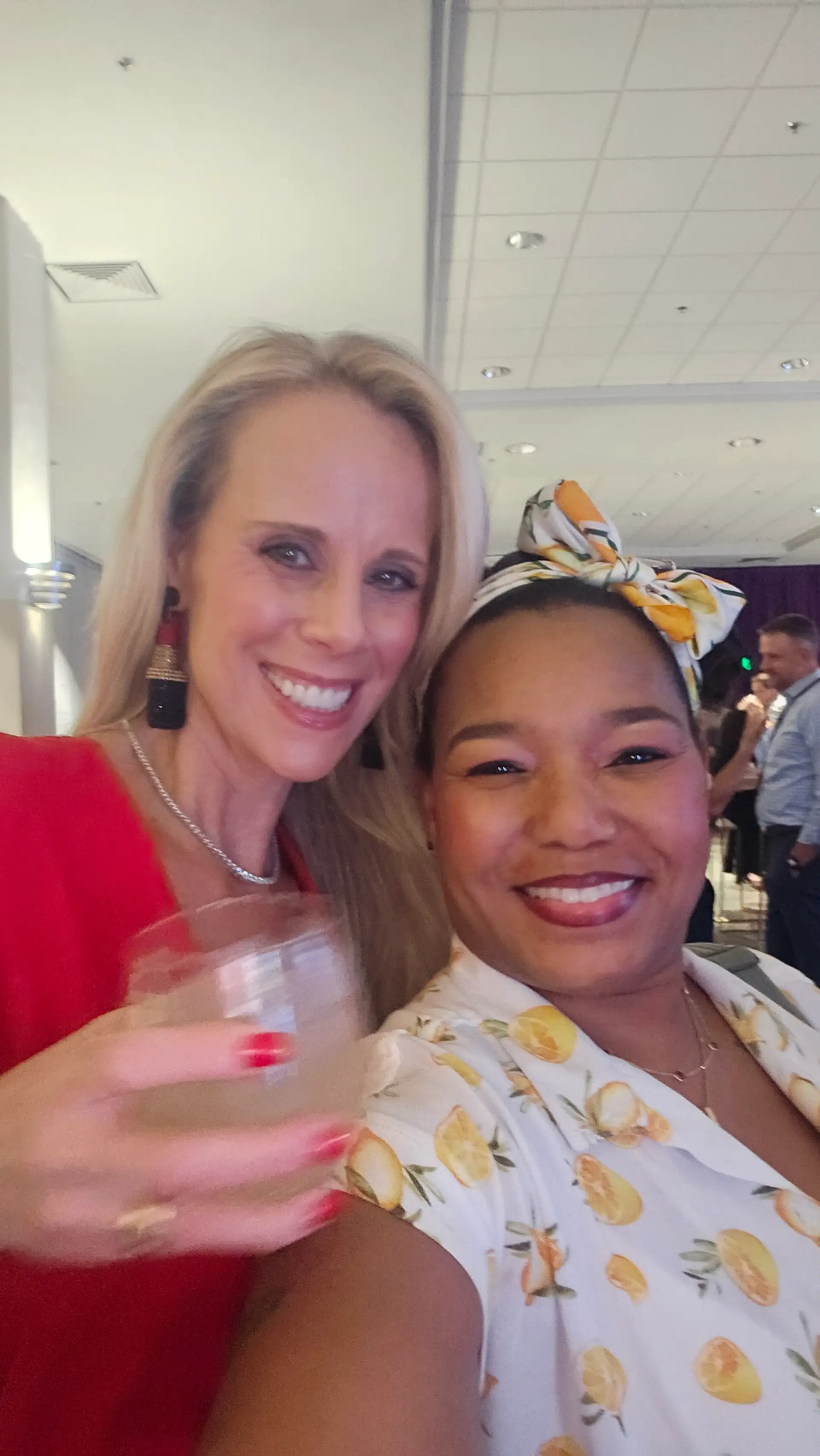 Two women posing for a picture, one holding a glass of Touch O Magic Lemonade.